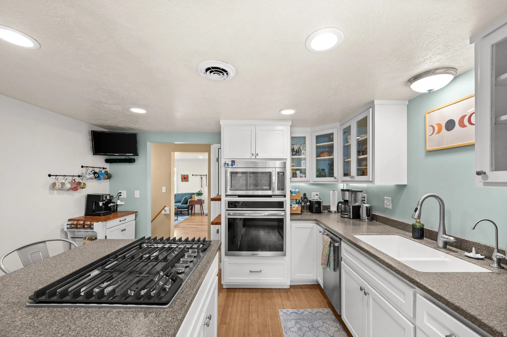 Kitchen featuring white cabinetry, built-in stainless steel appliances, a gas cooktop, and wood-finish flooring