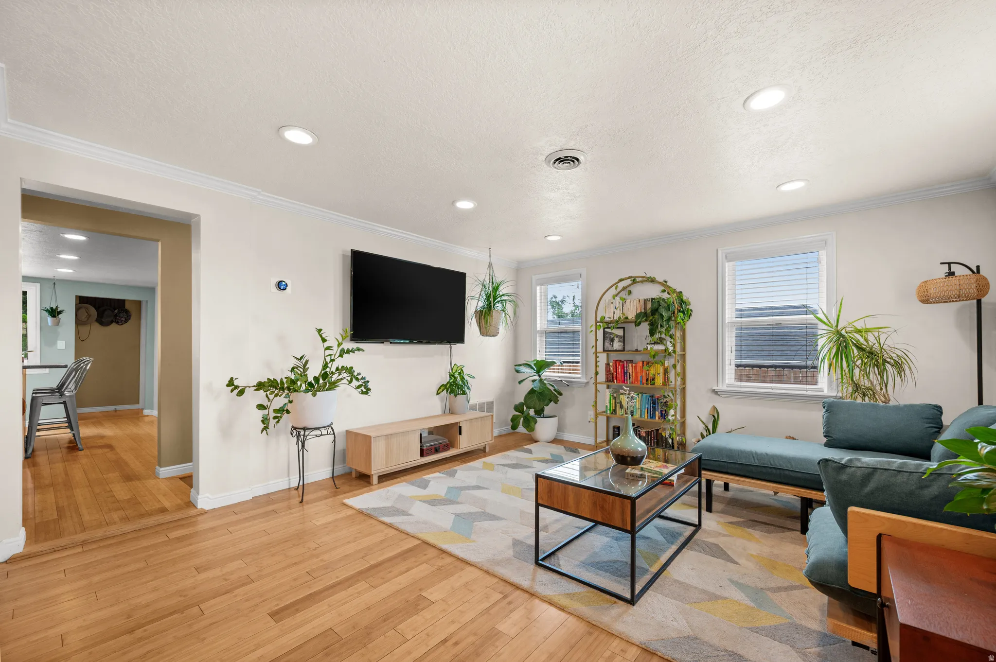 Recessed lighting throughout, crown molding, wood-finish flooring, white window frames, and cased openings