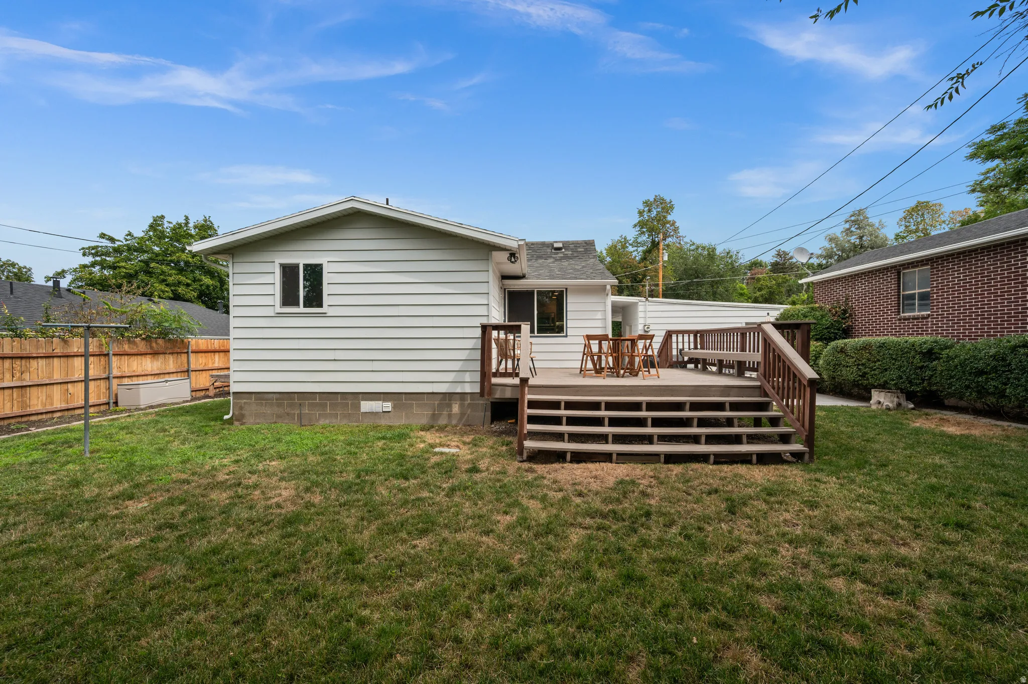 Expansive backyard featuring a multi-level wood deck, wood privacy fencing, and a white siding exterior