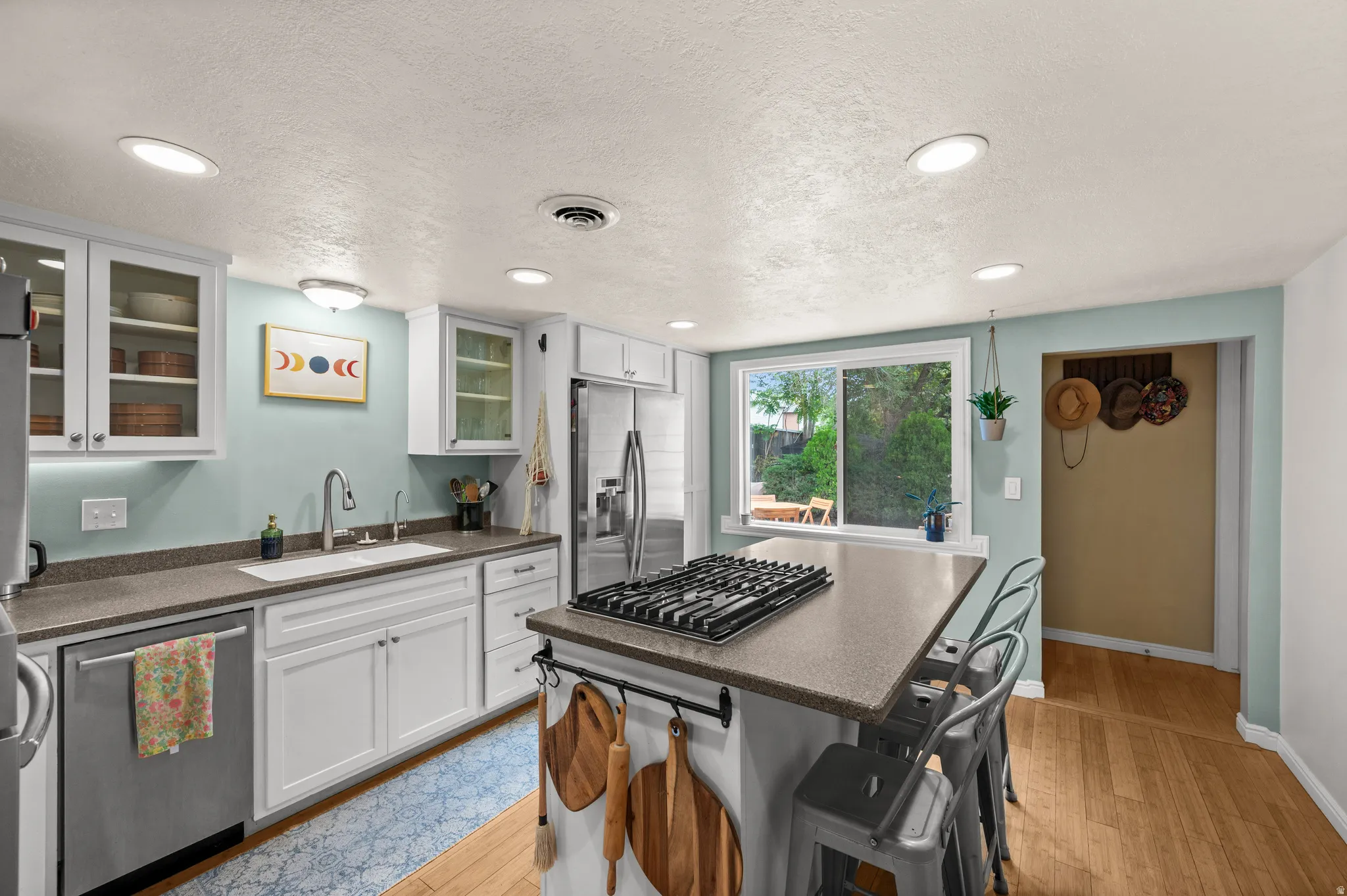 Kitchen featuring white cabinetry, a built-in stainless steel dishwasher, a center island with a gas cooktop, recessed lighting, and wood-finish flooring