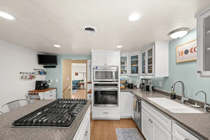 Kitchen featuring white cabinetry, built-in stainless steel appliances, a gas cooktop, and wood-finish flooring