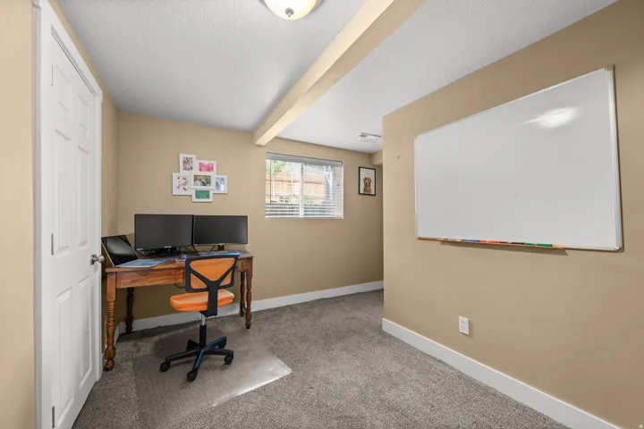 Carpeted room featuring a white door, a window with blinds, and a wall-mounted whiteboard