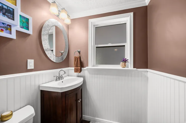 Dark wood-finish vanity with a curved basin, chrome faucet, and white beadboard paneling