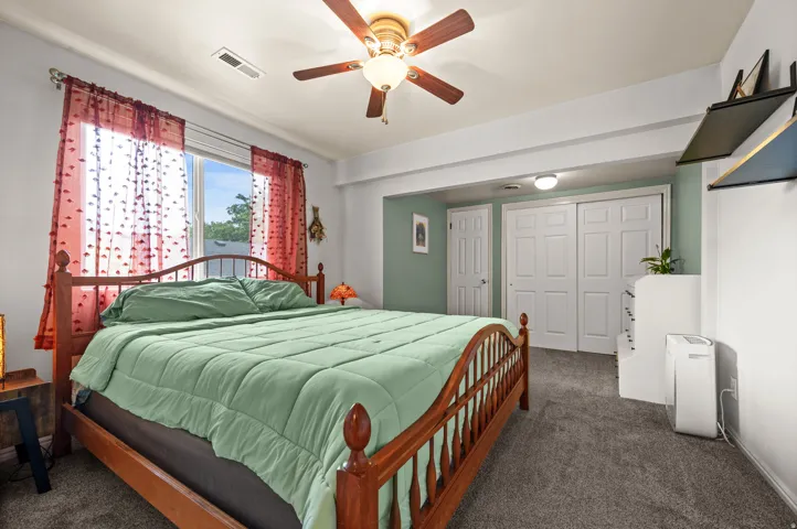 Wall-to-wall carpeting, window with natural light, ceiling fan, and sliding closet doors