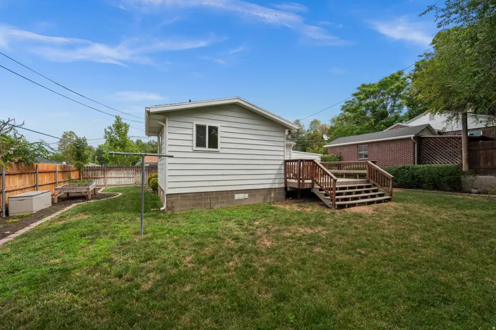 Expansive backyard with a wooden fence, featuring a raised garden bed and a multi-level wood deck