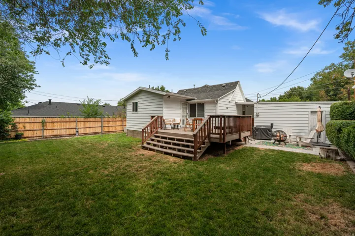 Expansive backyard featuring a wood privacy fence, a multi-level wood deck, and a stone patio area