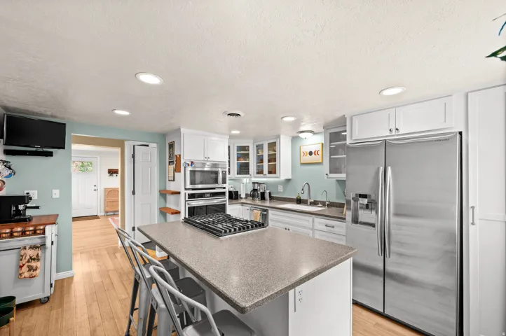 Kitchen featuring light wood-finish flooring, white cabinetry, a built-in oven, and a stainless steel refrigerator
