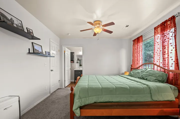 Recessed lighting, ceiling fan with light fixture, gray carpeting, crown molding, and a visible adjoining bathroom with a vanity