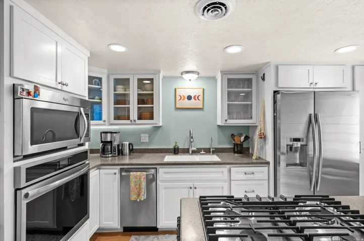 White cabinetry, stainless steel appliances, recessed ceiling lighting, undermount sink, and solid surface countertops
