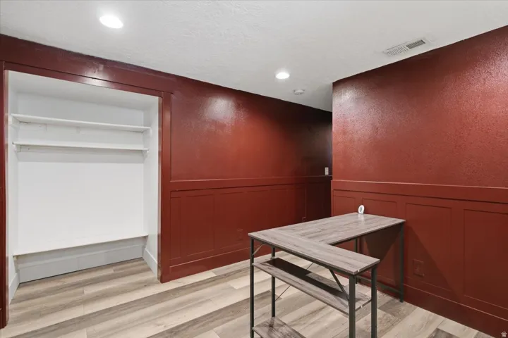 Wood-finish flooring, recessed lighting, built-in shelving, and wainscoting details