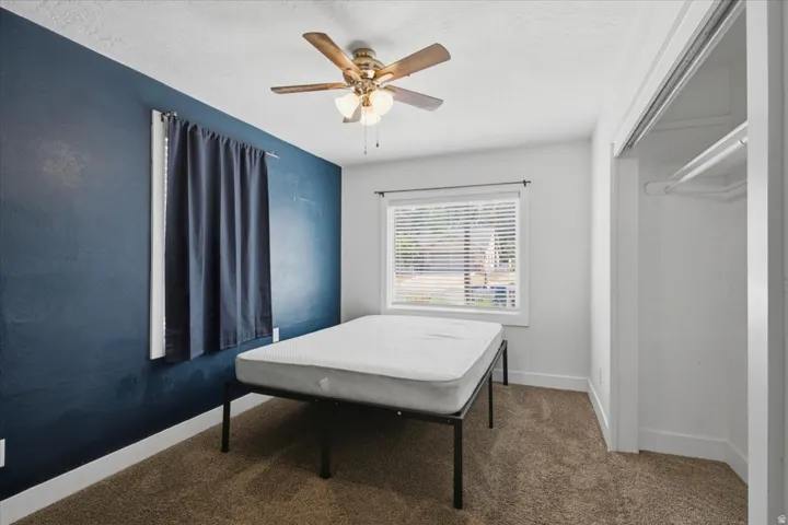 Ceiling fan with integrated lighting, carpeted flooring, window with blinds, and built-in closet with hanging rod
