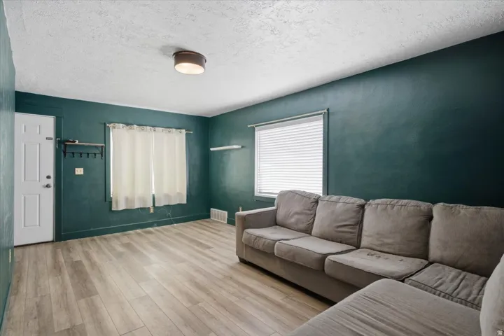 Wood-finish flooring, white paneled door, and a single-pane window with blinds