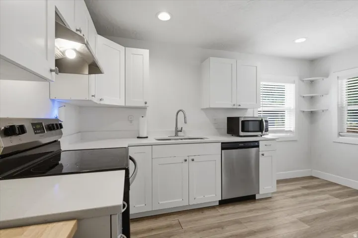 Kitchen featuring white cabinetry, light countertops, wood-finish flooring, stainless steel appliances, and recessed lighting