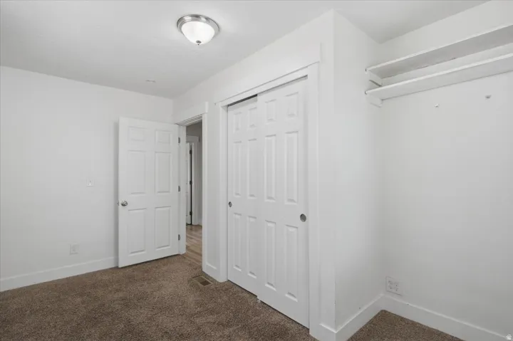 Plush carpeting, flush-mount ceiling light fixture, white painted walls, white trim, and sliding closet doors