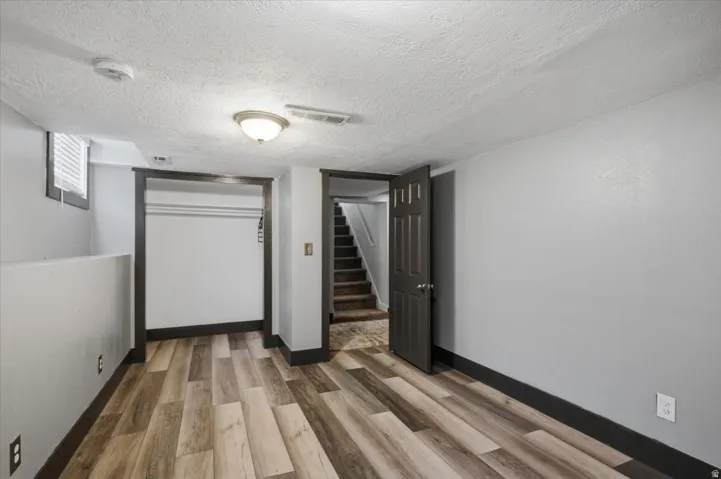 Wood-finish flooring, overhead lighting fixture, window with blinds, and built-in closet space