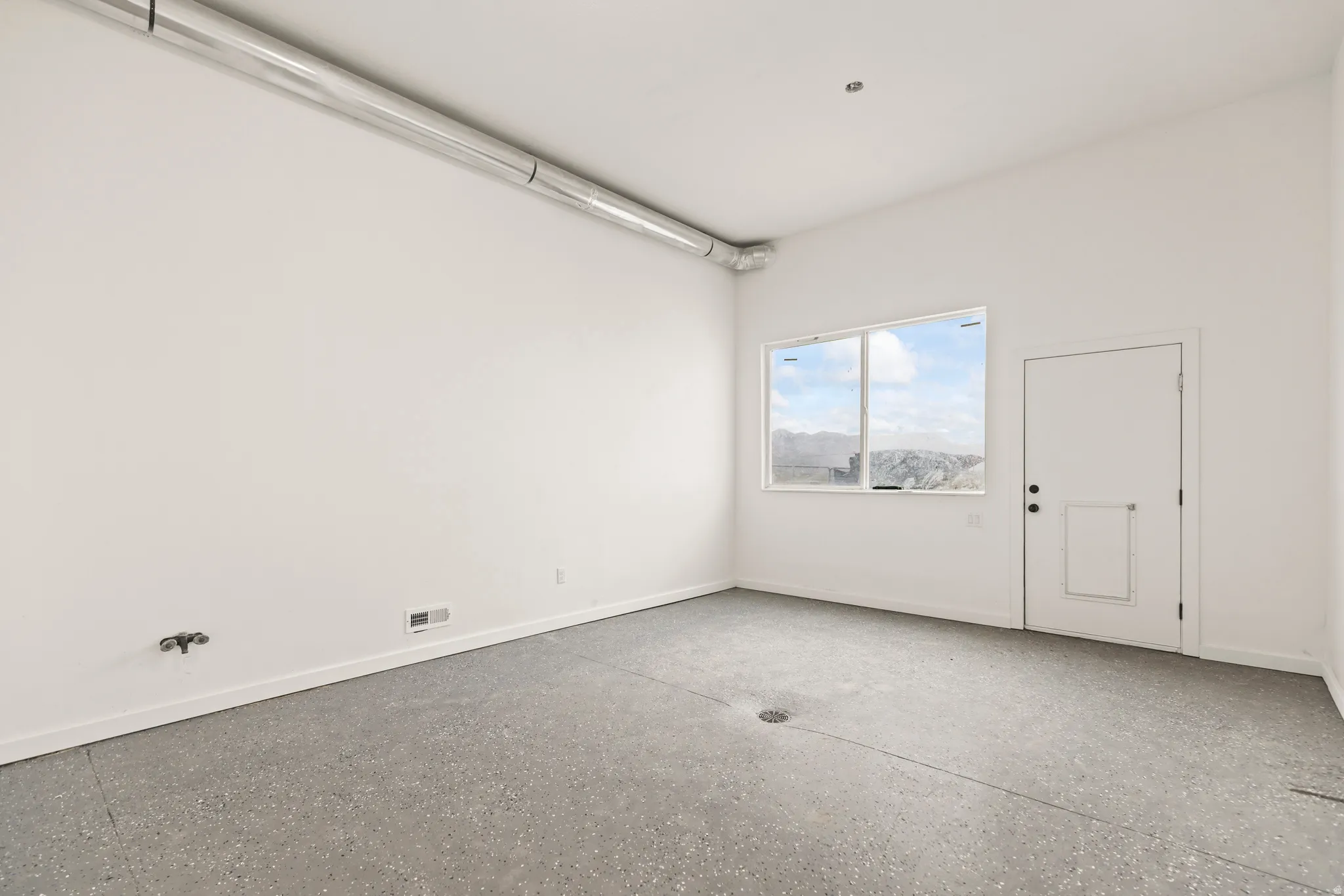 Polished concrete flooring, exposed overhead ductwork, and a window with mountain scenery