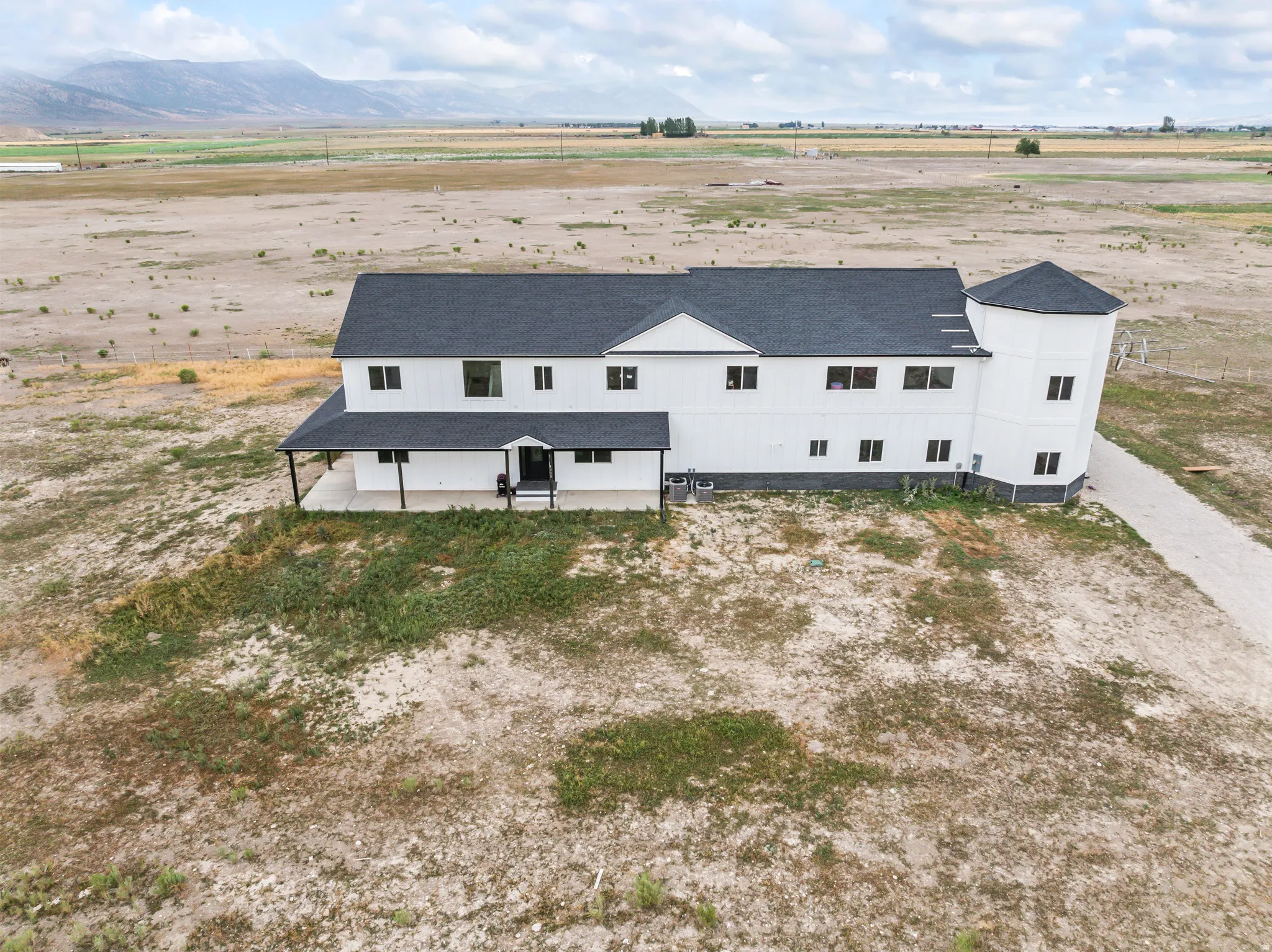 Modern farmhouse-style exterior with black trim windows, a covered front porch, and a gravel driveway