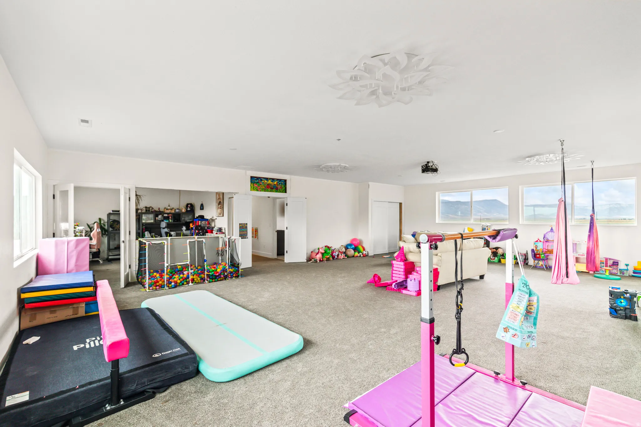 Expansive carpeted room featuring multiple windows, white walls, and decorative ceiling lighting