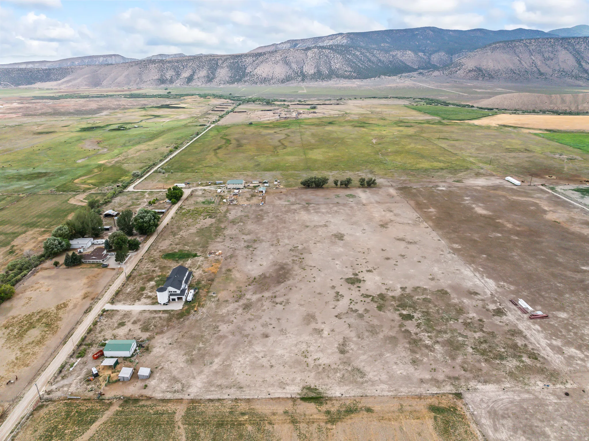 Expansive acreage with established residential structure, secondary outbuildings, and distant mountain backdrop