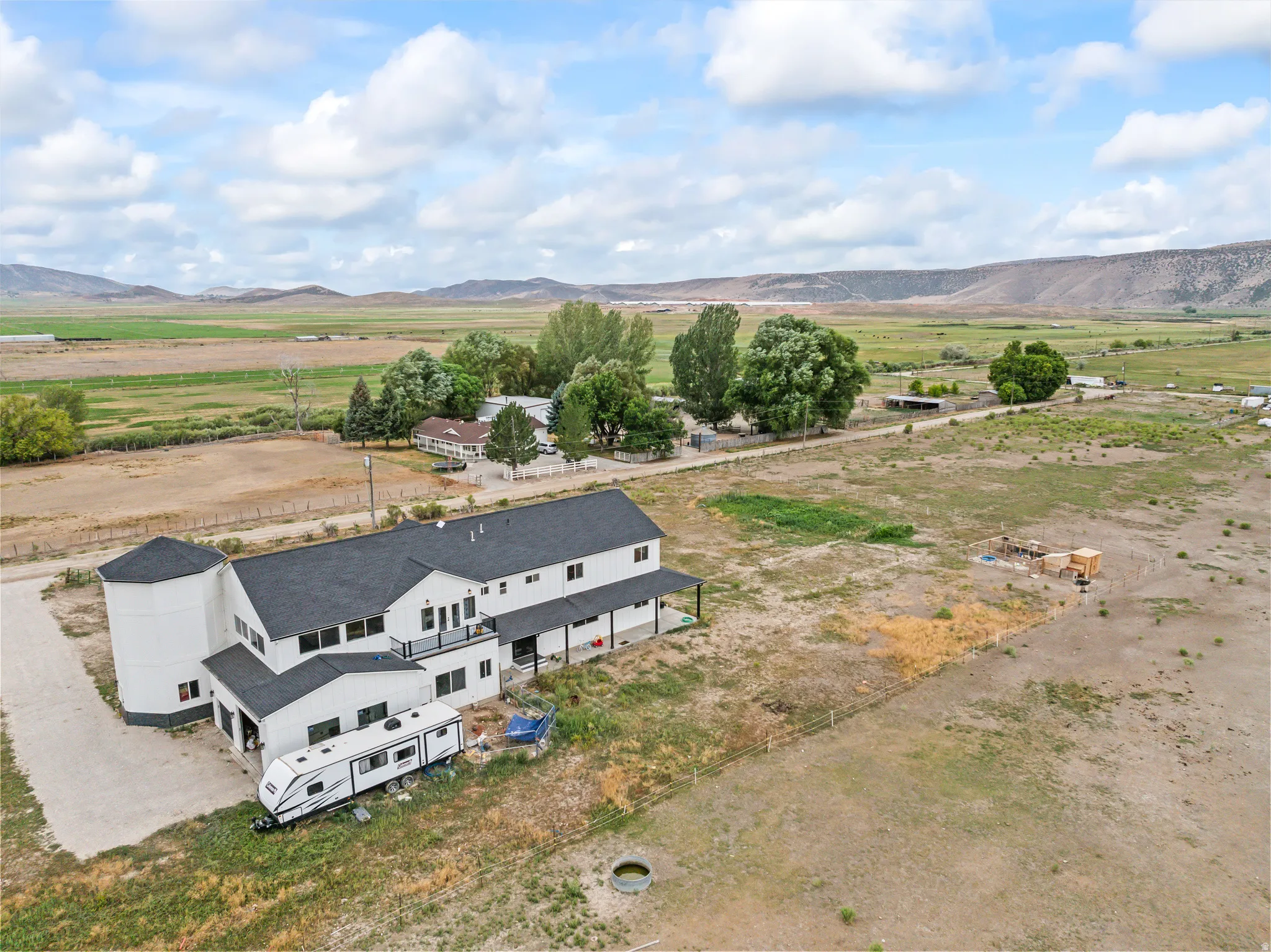 Expansive property featuring a two-story residence with dark roofing, a white exterior, and an attached silo structure