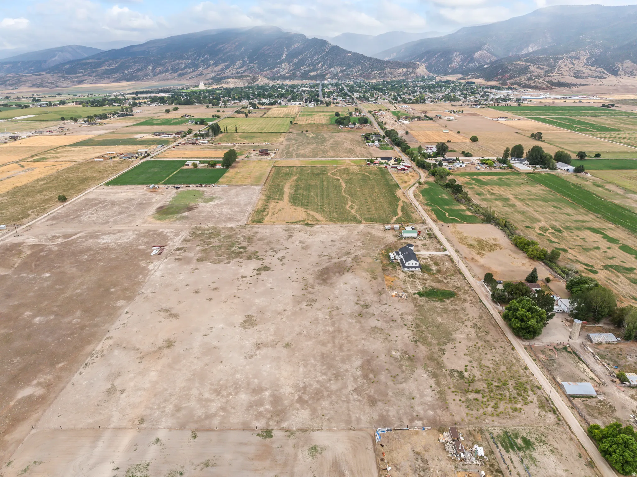 Expansive rural landscape featuring a mix of open fields, cultivated land, and distant mountain ranges