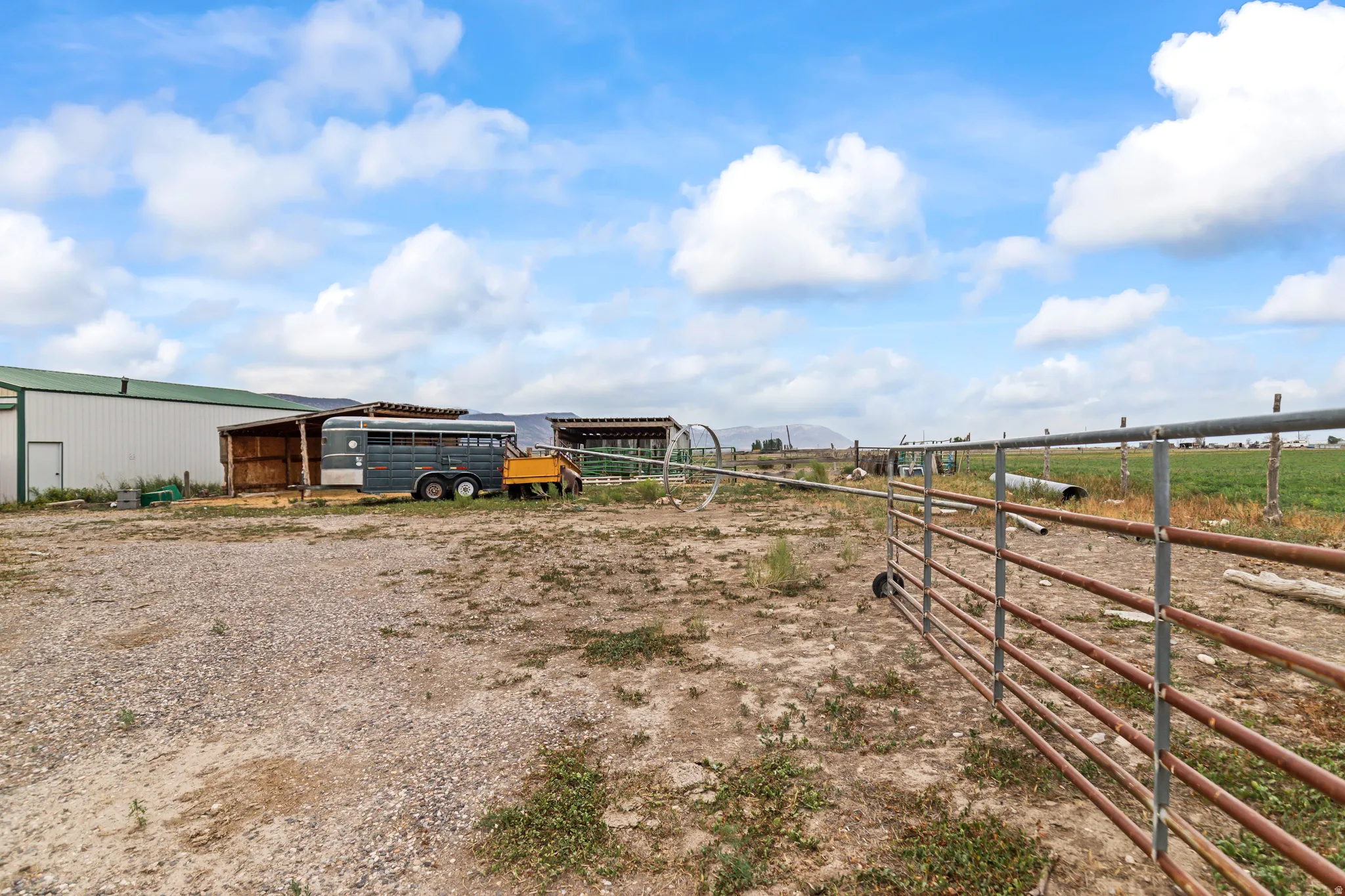 Gravel terrain with a metal gate and a white and green exterior building