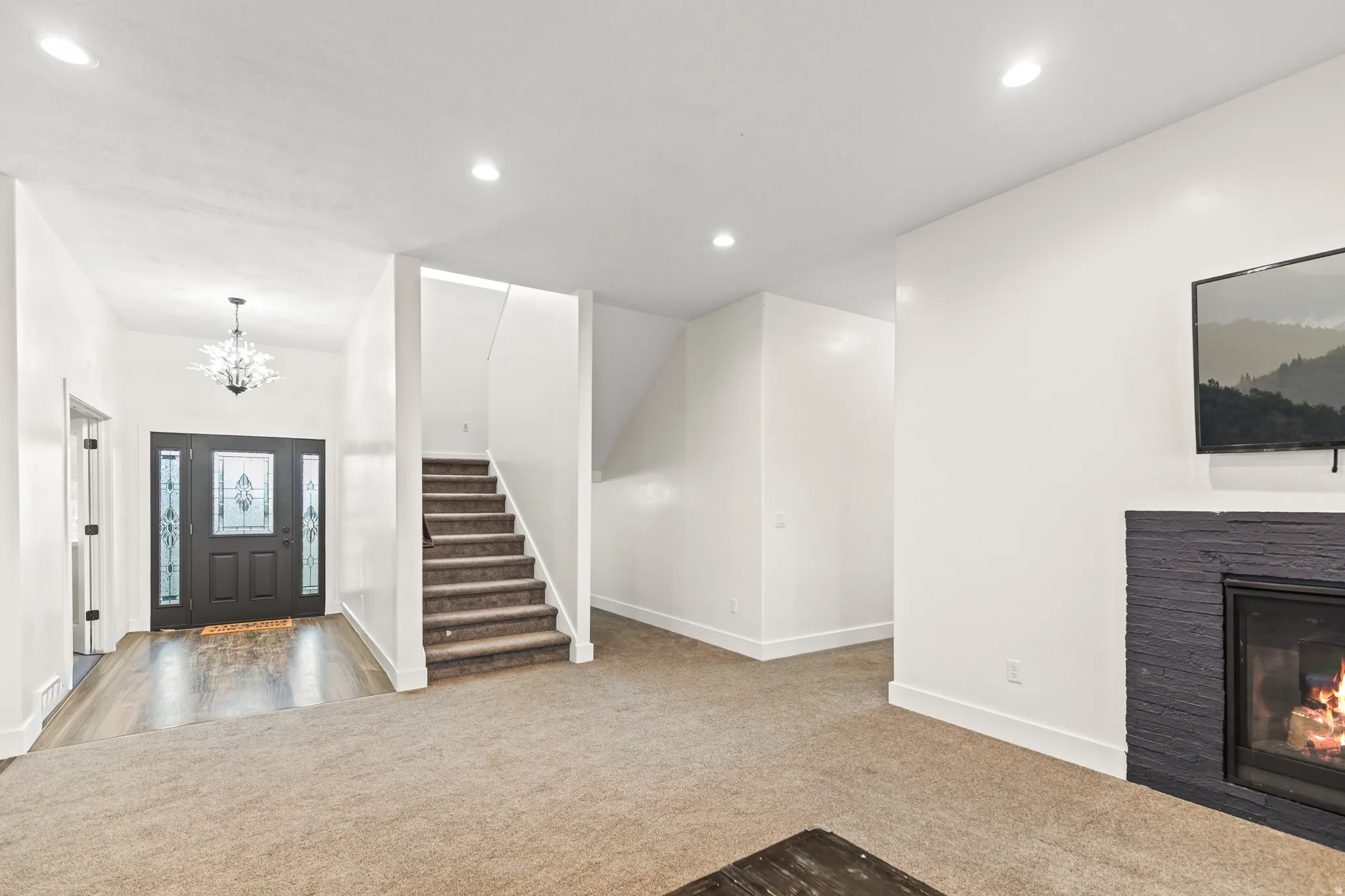Entryway featuring a decorative pendant light, a dark-stained front door with leaded glass inserts, and wood-finish flooring