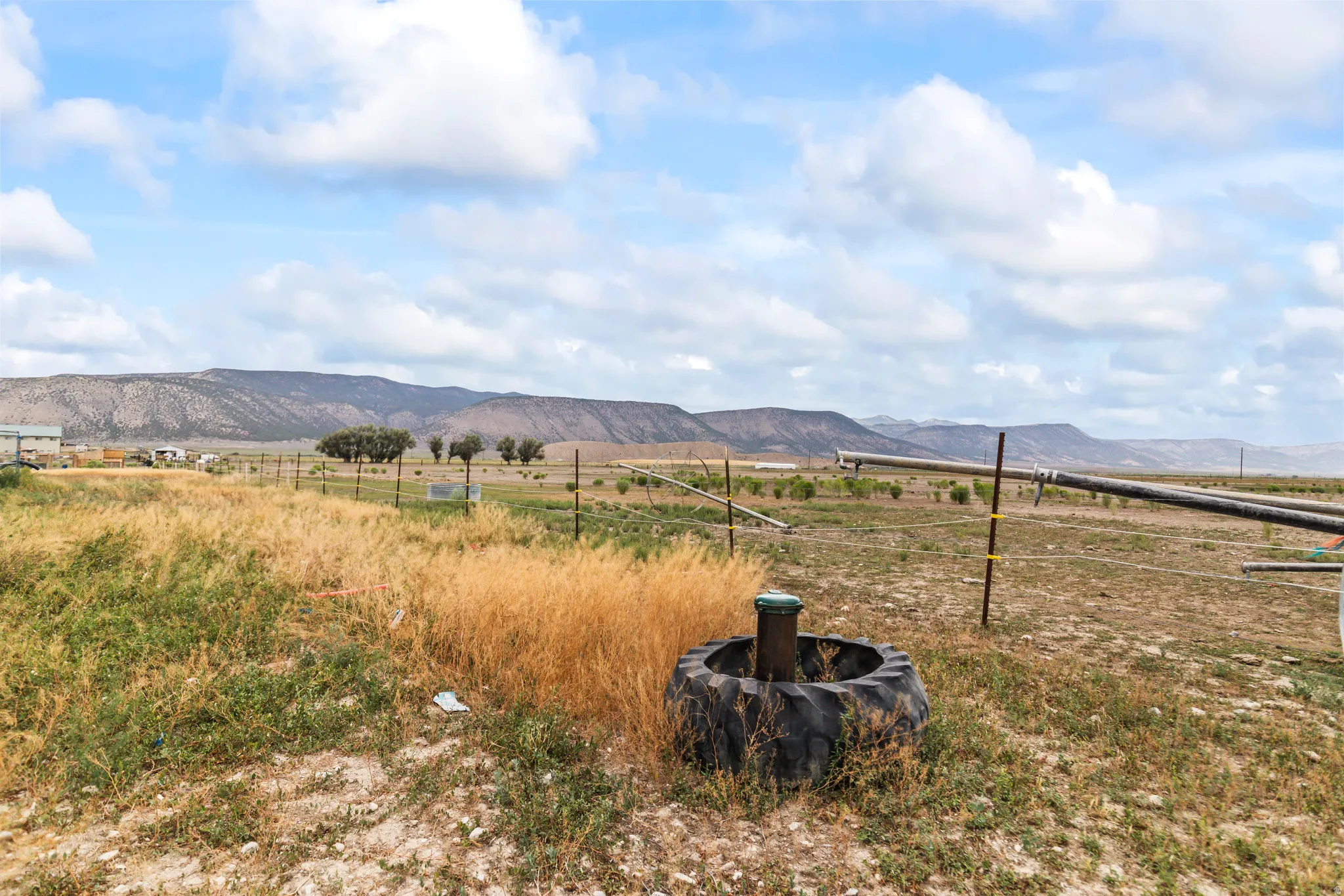 Expansive open land featuring distant mountain ranges and a partially visible agricultural irrigation system