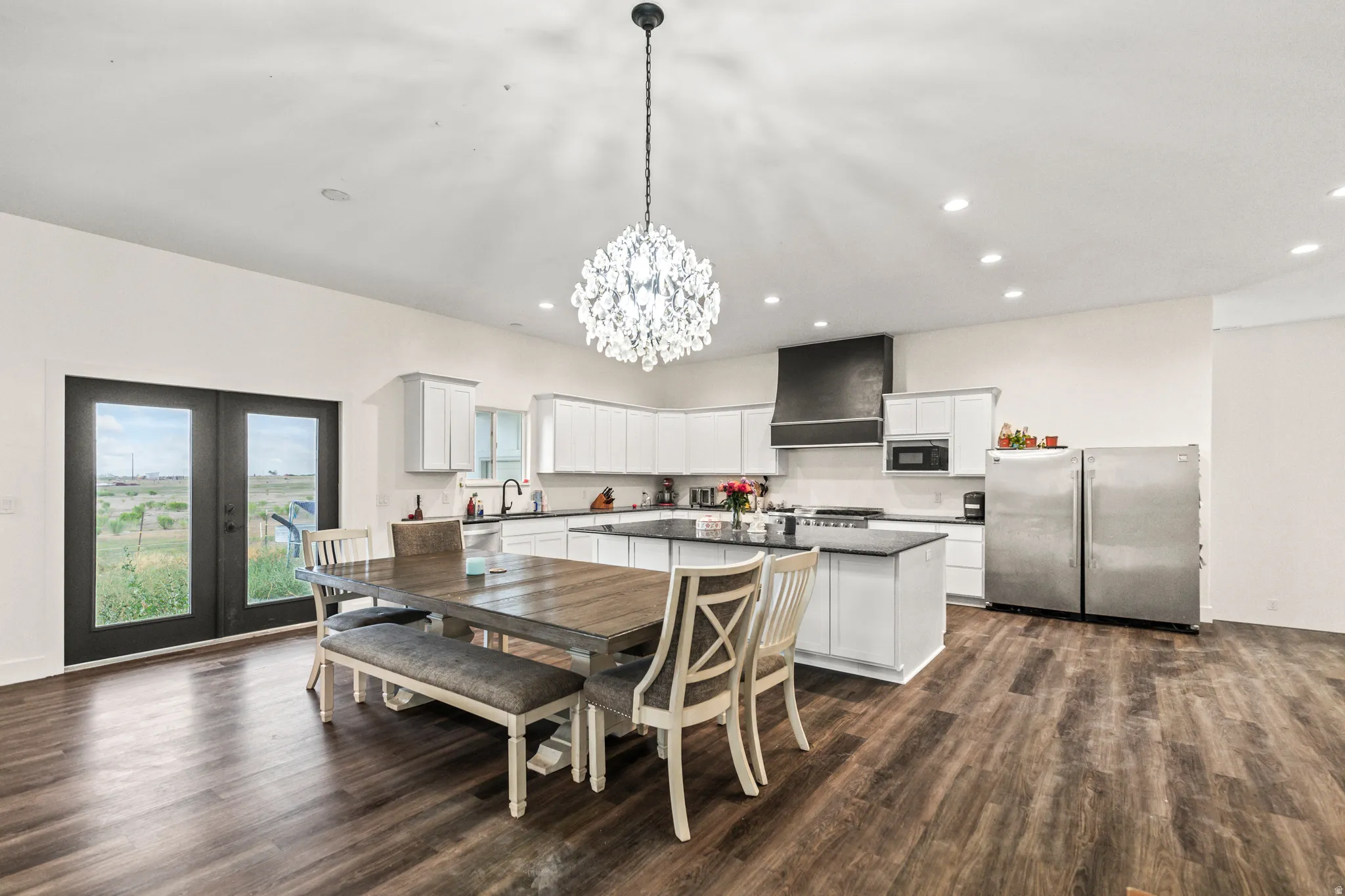 Spacious kitchen with white cabinetry, a central island, stainless steel appliances, and wood-finish flooring