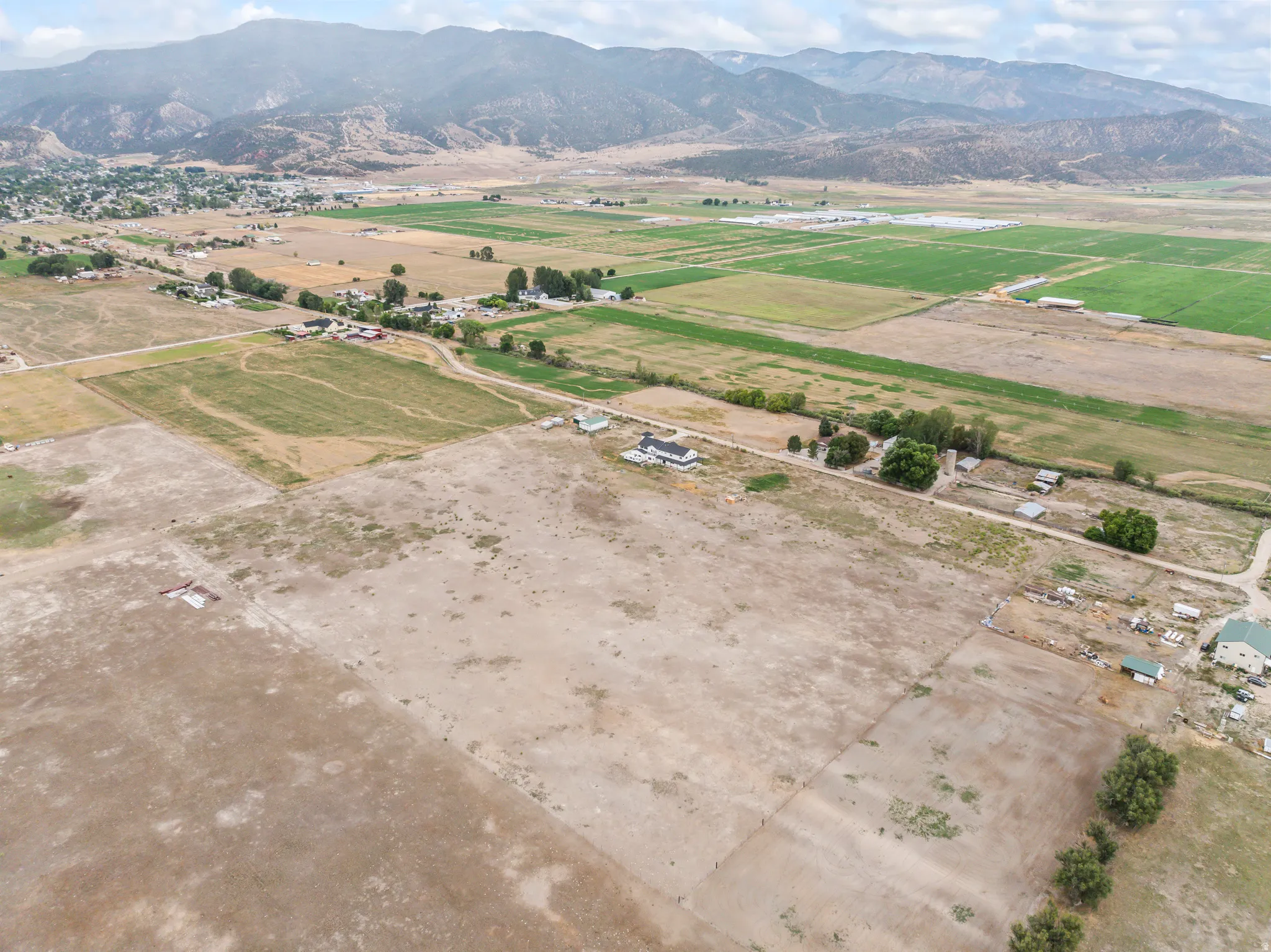 Expansive acreage featuring a white residence, outbuildings, and cultivated fields