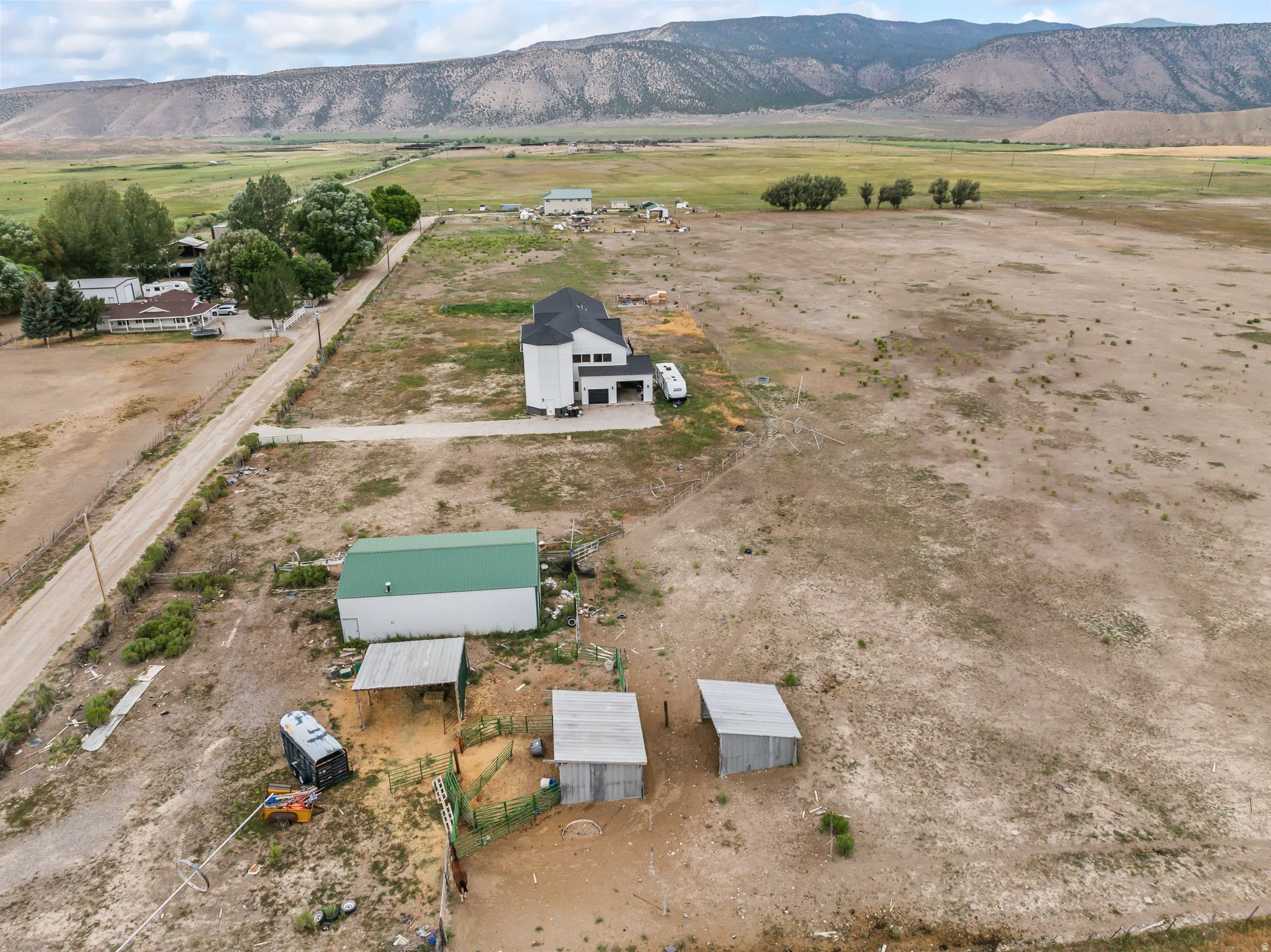 Expansive property featuring a contemporary residence, multiple outbuildings, and mountain backdrops