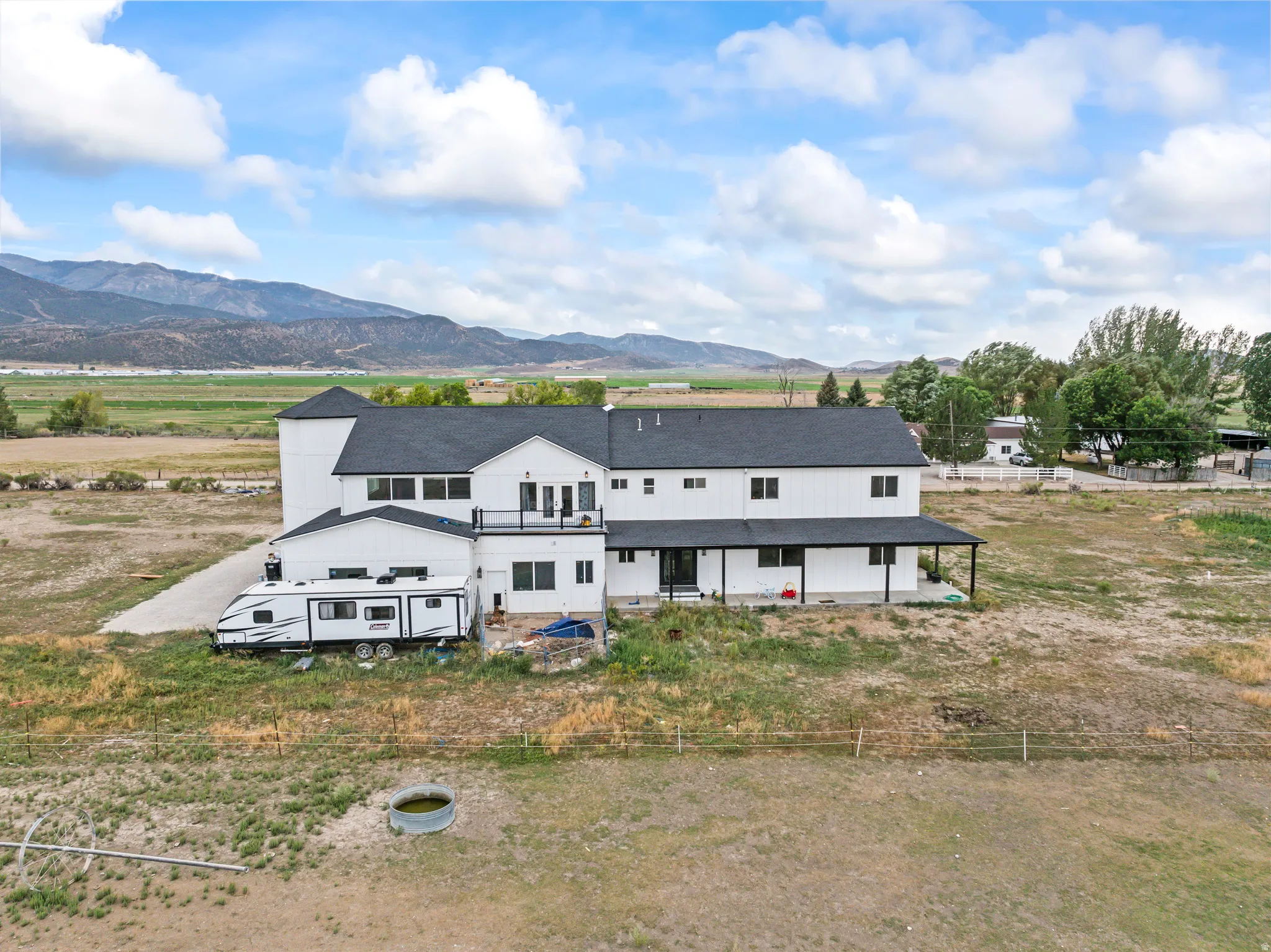White siding exterior with a dark roof and mountain backdrop