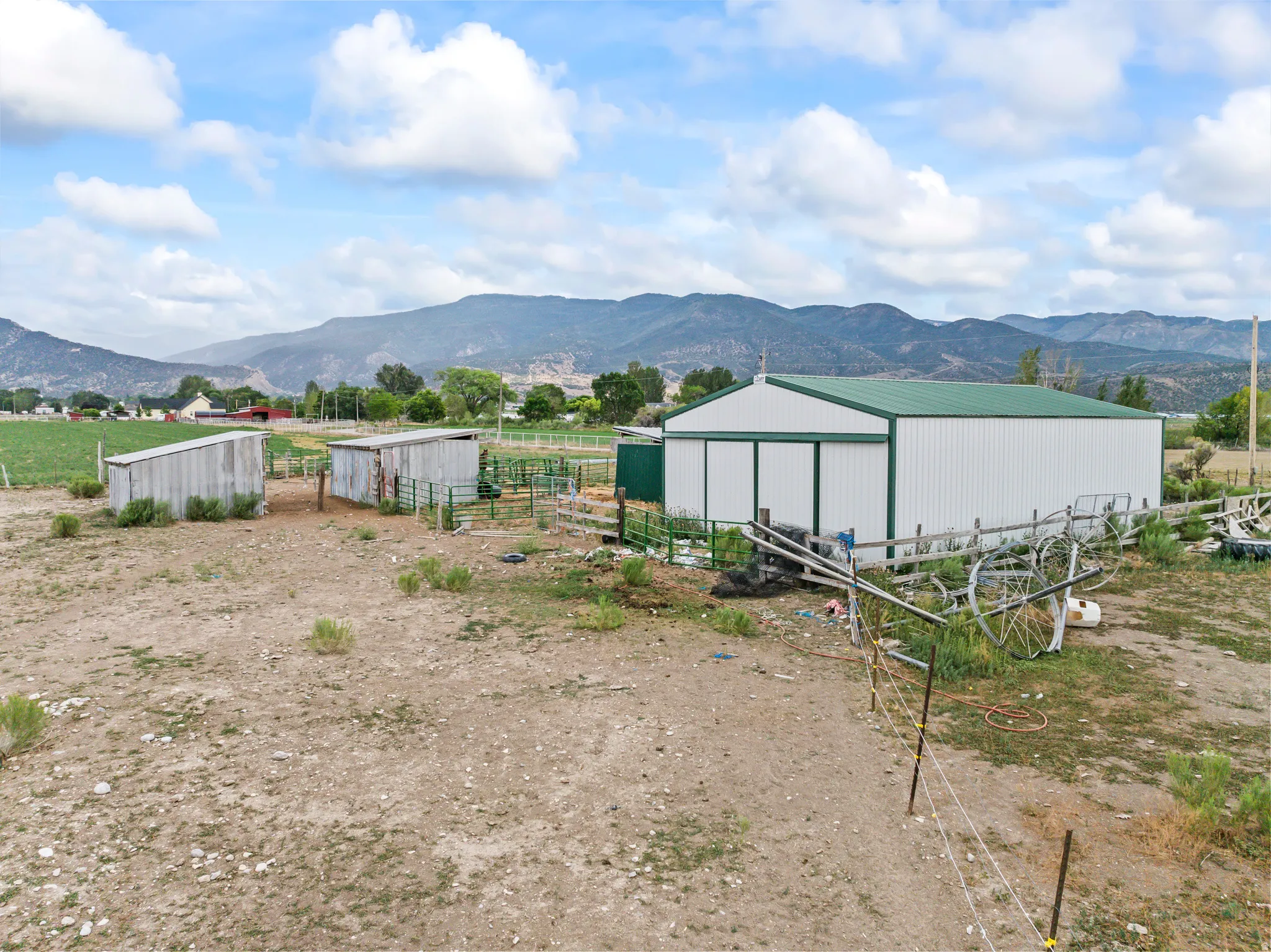 Large metal outbuilding with a green roof, accompanied by two smaller wooden outbuildings