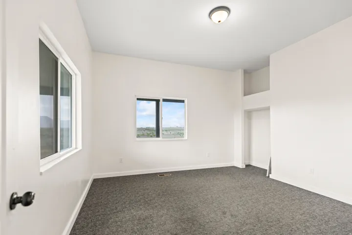 Neutral wall tones, gray carpeting, dual windows, and an integrated ceiling light fixture