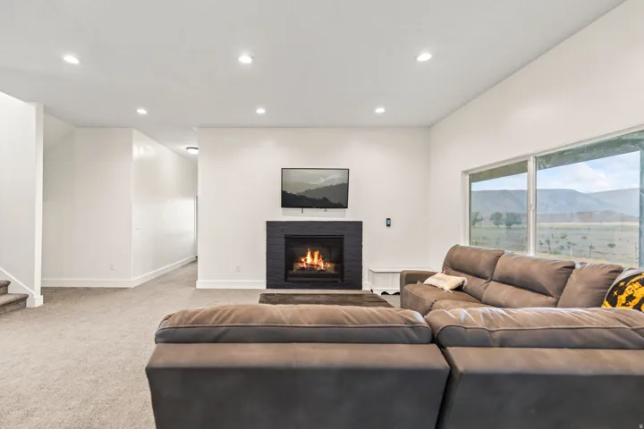 Spacious living area featuring a dark tile fireplace surround, large windows, recessed lighting, and light carpet flooring