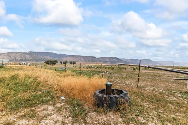 Expansive open land featuring distant mountain ranges and a partially visible agricultural irrigation system