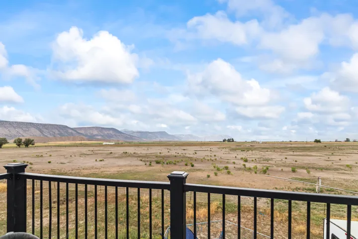 Expansive open landscape with distant mountains, black metal deck railing, and open sky