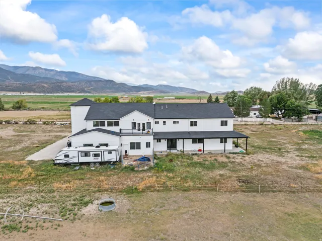 White siding exterior with a dark roof and mountain backdrop