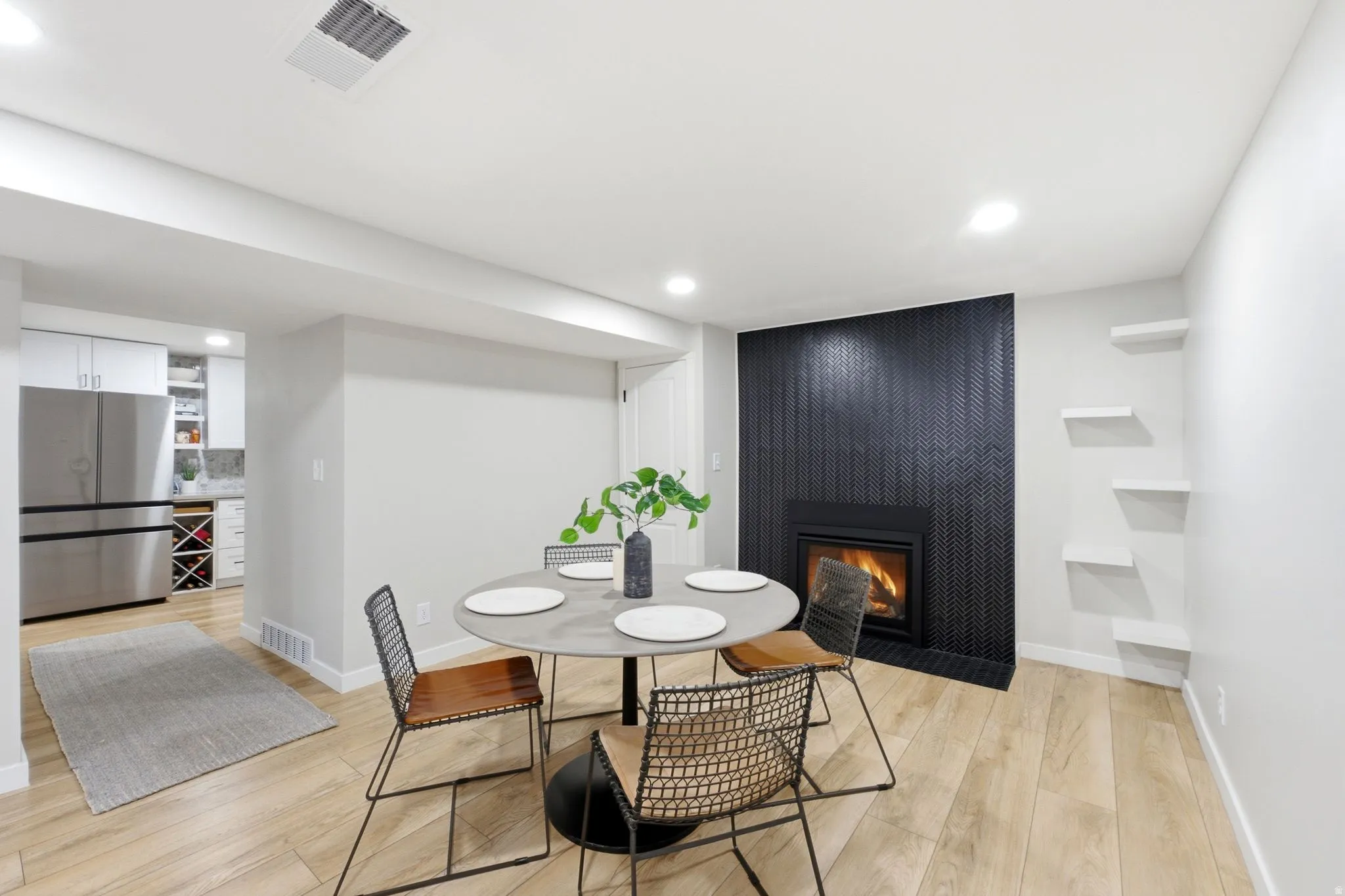 Modern dining area featuring a round white table, light wood-finish flooring, and recessed ceiling lighting