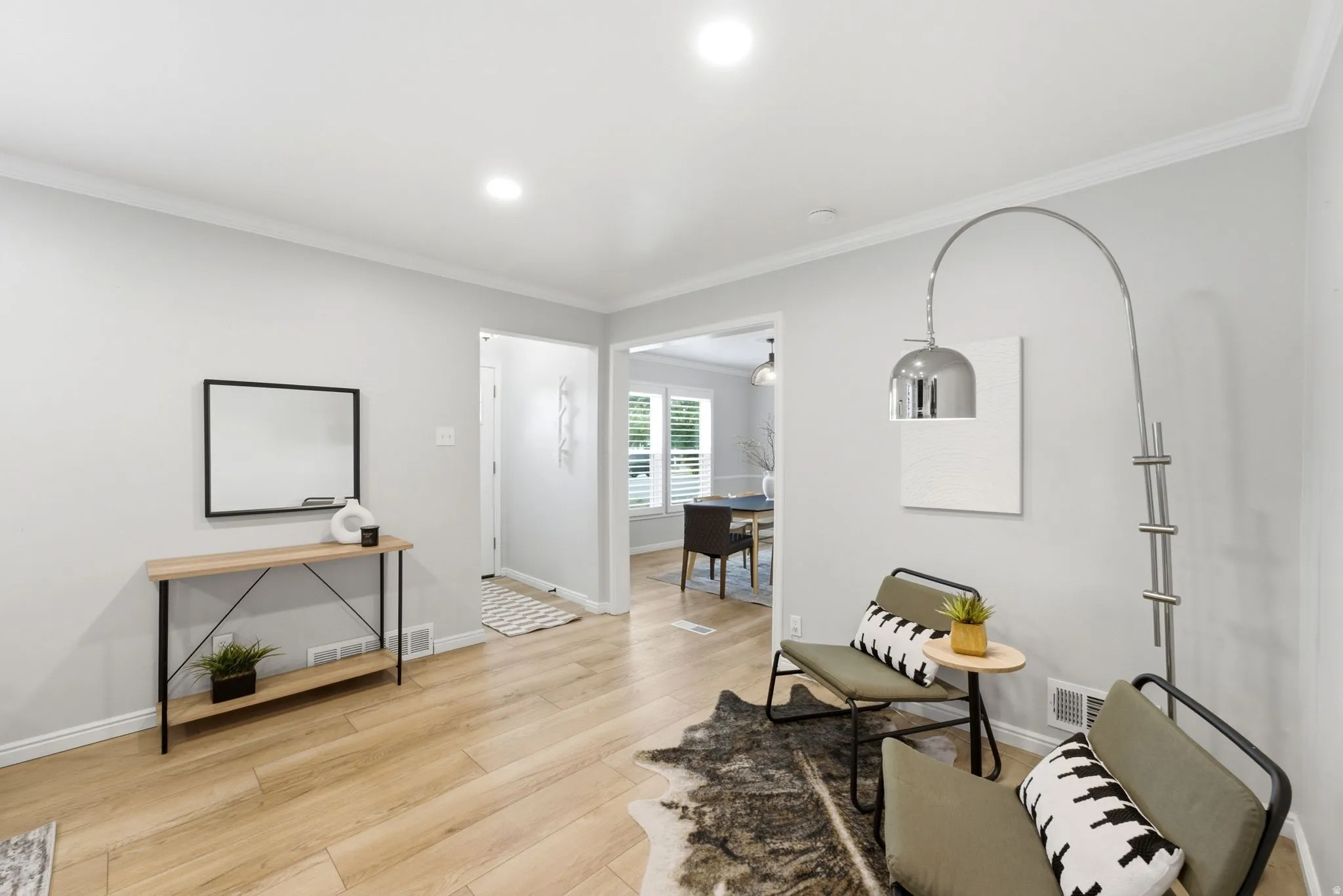 Bright, open living space featuring warm wood-finish flooring, recessed ceiling lighting, and large glass doors opening to additional rooms