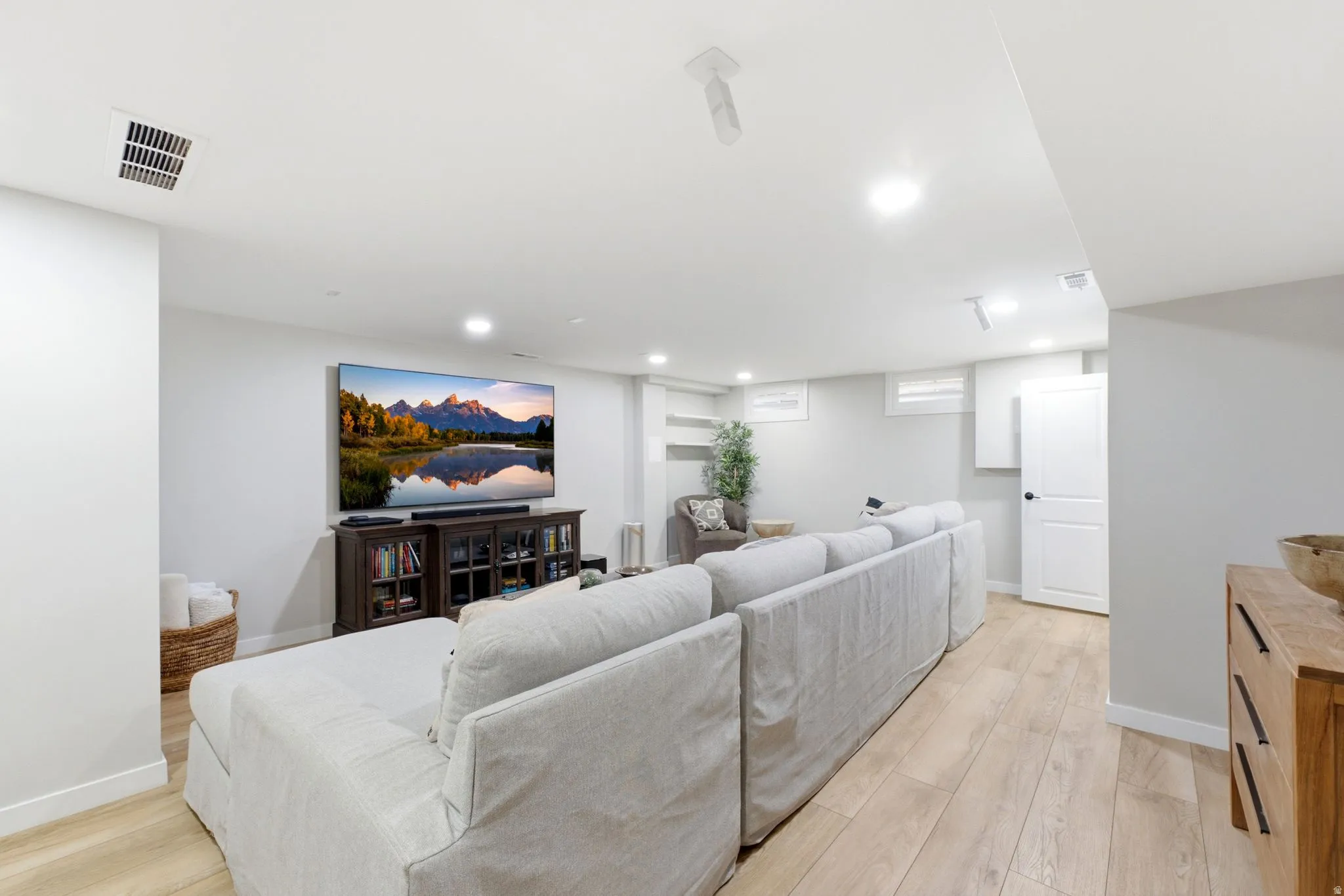 Recessed lighting, wood-finish flooring, white walls, built-in shelving, and a white interior door