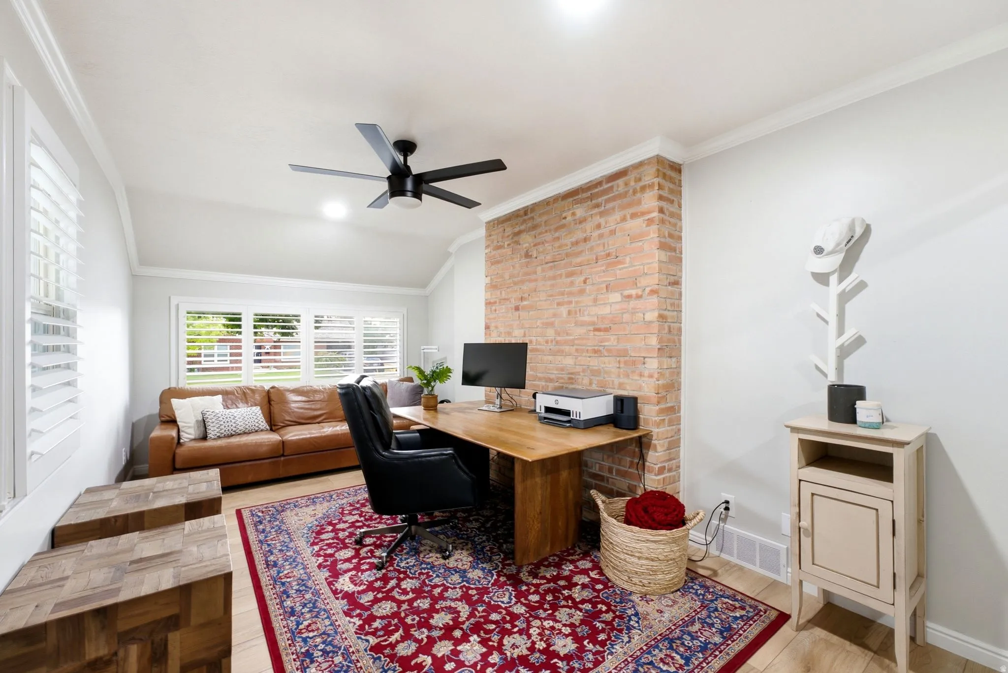 Recessed lighting, exposed brick accent wall, wood-finish flooring, crown molding, and plantation shutters