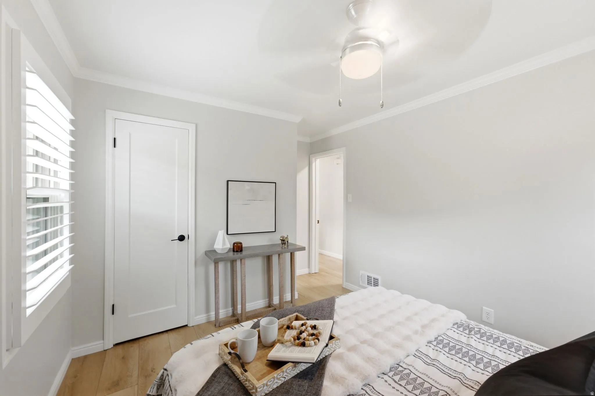 White plantation shutters, crown molding, a ceiling fan with integrated lighting, wood-finish flooring, and white interior doors