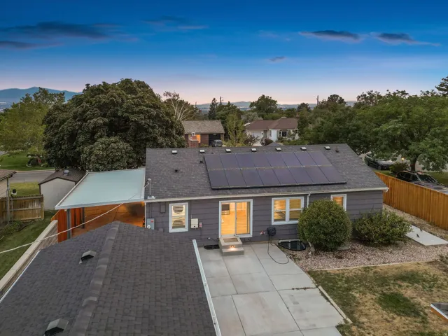 Modern home featuring a charcoal-toned roof with integrated solar panels, expansive composite patio with clean geometric lines, and updated exterior cladding