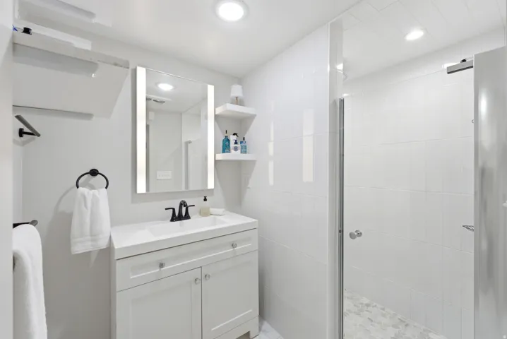 White vanity with integrated sink, black faucet, and illuminated mirror