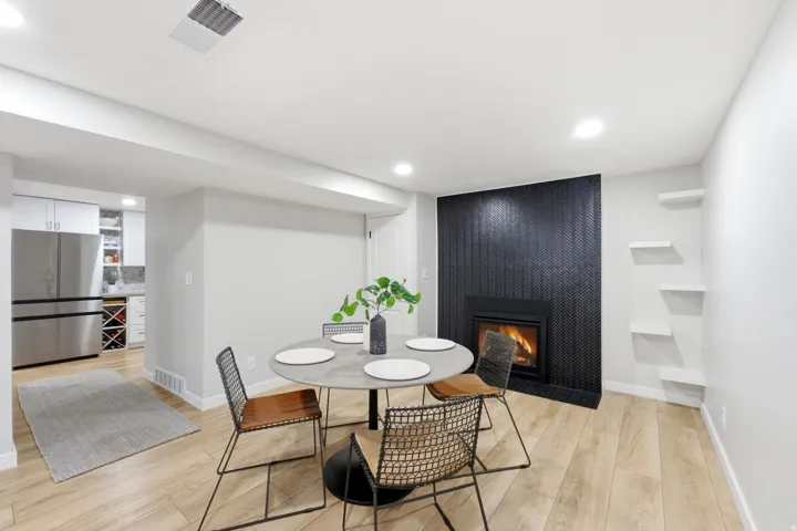Modern dining area featuring a round white table, light wood-finish flooring, and recessed ceiling lighting