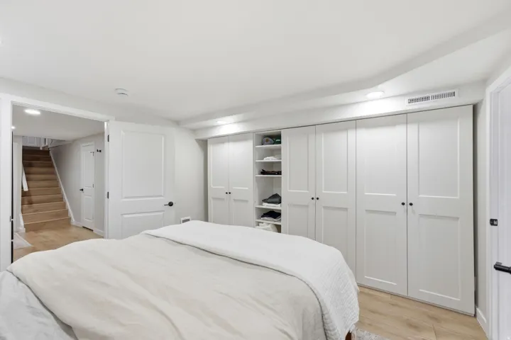 Built-in white paneled wardrobe with open shelving, recessed lighting, and wood-finish flooring