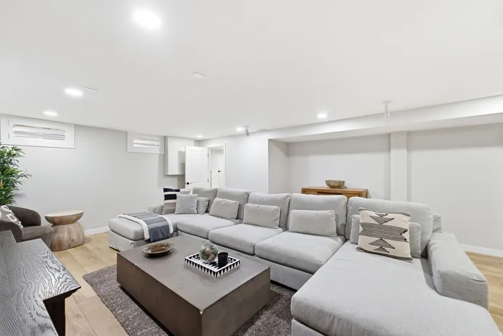 Recessed lighting, wood-finish flooring, white walls, and a white paneled door