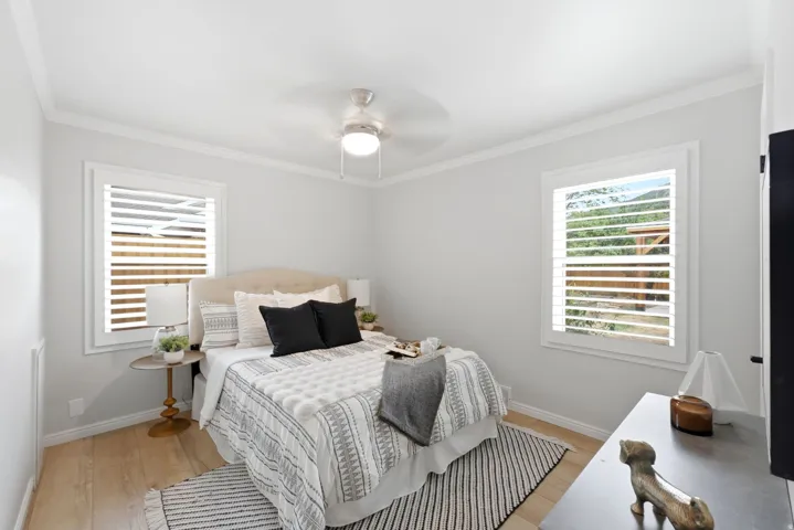 Wood-finish flooring, crown molding, and a ceiling fan with integrated lighting