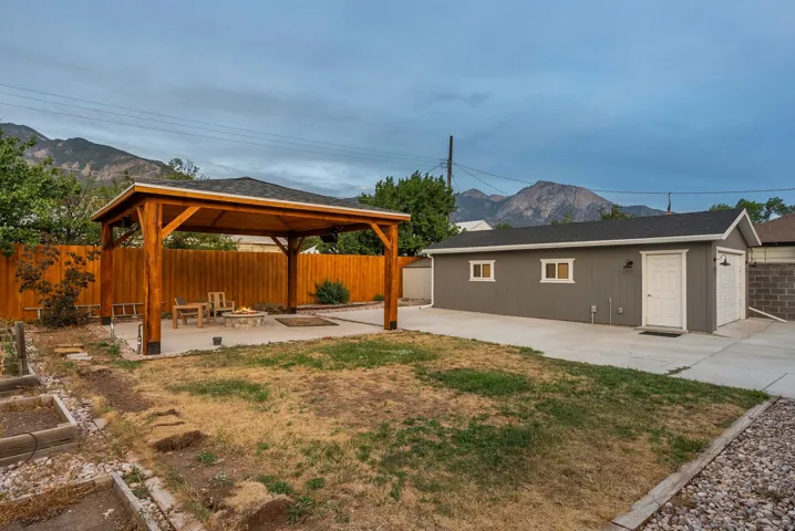 Expansive backyard retreat featuring a custom wood-frame pergola with integrated seating area, mature landscaping, and manicured lawn